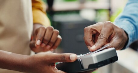 Pay by payment terminal. Paying with contactless credit card with NFC technology. Bartender with a credit card reader machine at bar counter with male holding credit card. Focus on hands.