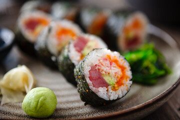 Sushi maki rolls with tuna, flying fish caviar, crab, avocado on a plate with chopsticks, soy sauce, wasabi and ginger. Japanese traditional food closeup served for lunch in modern gourmet restaurant