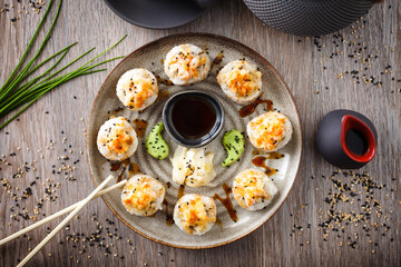 Baked sushi maki rolls with prawns and crab on a plate with chopsticks, soy sauce, wasabi and ginger. Japanese traditional fish food closeup served for lunch in modern gourmet restaurant