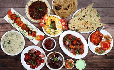 Assorted indian food on wooden background. Chicken Tikka, chicken biryani, chilli chicken, chicken manchurian, tandoori chicken, ulcha, paratha and jeera rice.. Dishes and appetizers of indian cuisine