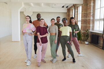 Portrait of multiethnic group of dancers smiling at camera while standing in dance studio