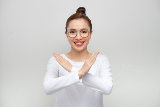 Portrait happy Asian beautiful young woman confident holding two crossing arms say no X sign on white background