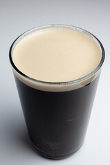 Glass of dark beer on white background
