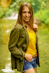 Obraz premium PRETTY GIRL WITH A GREEN SHIRT IN THE RIVER WHILE IS SMILING