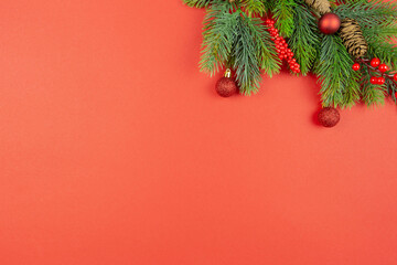 Christmas festive red decorations, fir tree branches on red background. Flat lay. Top view. Copy space. Template composition.