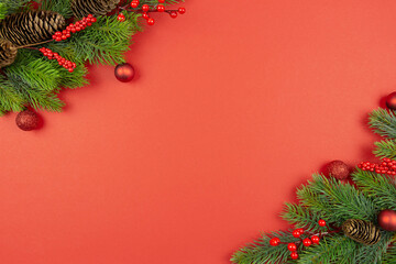 Obraz na płótnie Canvas Christmas festive red decorations, fir tree branches on red background. Flat lay. Top view. Copy space. Template composition.