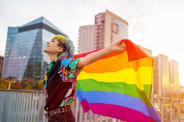 Portrait of happy non-binary person waving rainbow flag
