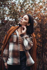 Obraz premium Outdoor fashion photo of young beautiful lady in autumn landscape with dry flowers. Knitted sweater, wine lipstick. Warm Autumn. Warm Spring