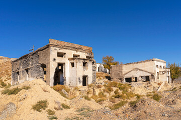 Fototapeta premium An old abandoned factory in the mountains. Fragments of destroyed buildings. Mountains.Ruins of a poly metal factory.Abandoned industrial production.The ruins of a mining and processing plant.Blue sky