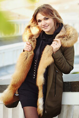  blond business woman in fox fir dawn jacket with hood closeup photo on city park background