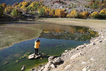 man in yellow raincoat taking a photo in the lake