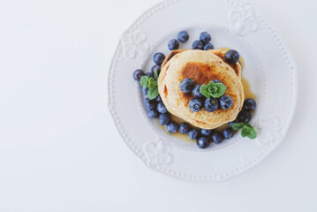 Stack of homemade small thick pancakes served with fresh blueberries.