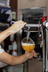 A bartender pouring draft beer into a glass