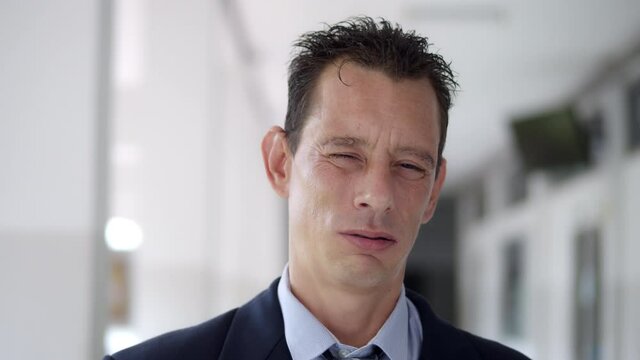 A businessman wearing a suit and a tie is suffering from abnormal gasping for breath.