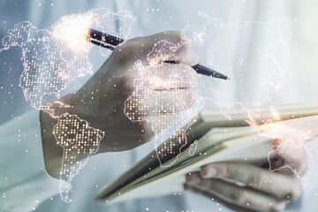 Double exposure of abstract digital world map and man hand writing in notebook on background, research and strategy concept