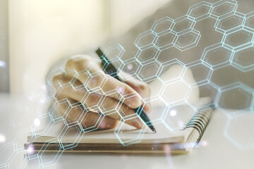 Creative abstract wireless technology hologram with hexagon and man hand writing in diary on background, artificial intelligence and machine learning concept. Multi exposure