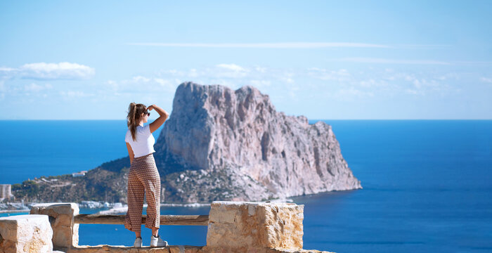 Calpe coast, tourist woman looking at Calpe or Calp coast and penon the ifach or Penyal d'Ifac Natural Park from path above the city in the morro de Toix