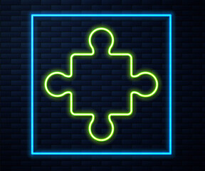 Glowing neon line Puzzle pieces toy icon isolated on brick wall background. Vector.