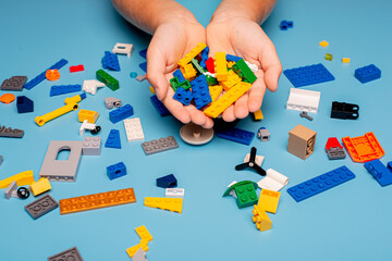 Close up of child's hands playing with colorful plastic bricks at the table