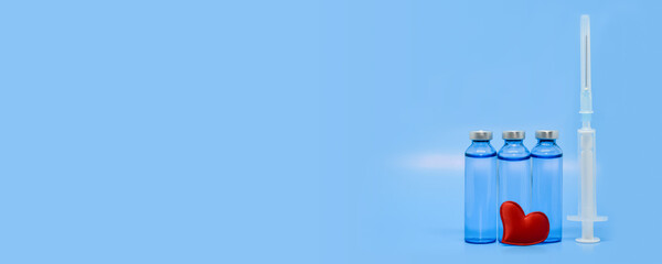 Glass medical ampoules, syringe and red heart on a light blue background. Healthcare concept:...