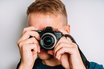 Young man takes photos and looks through the viewfinder, isolated on a white background