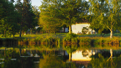Fototapeta premium Magnifiques reflets de maisons typiques landaise sur un petit étang, éclairé par la lumière du soleil couchant