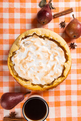 Pear pie with cream, homemade pastries on the table with a orange napkin, coffee and spices. Copy space.