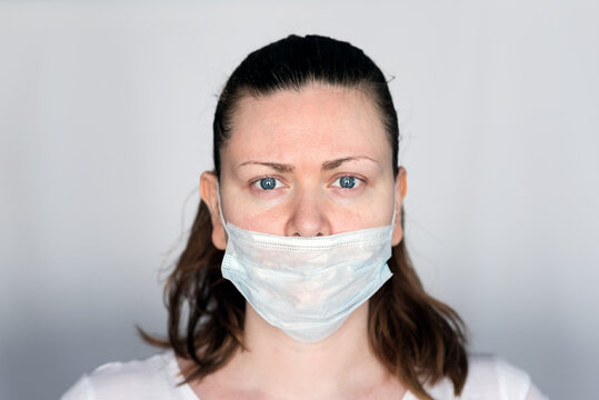 Young Woman Demonstrates The Wrong Way To Wear A Mask To Avoid The Spread Of Coronavirus Covid-19,  With The Nose Out Of The Mask