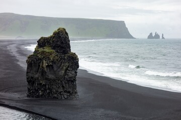 Detail of Arnardrangur rock in the middle of peninsula near Reynisfjara Beach view point (Dyrholaey) in rainy weather