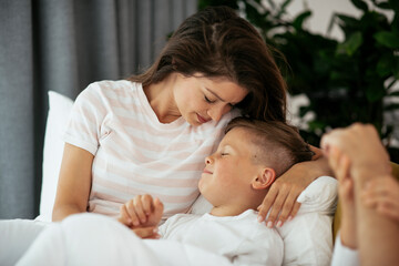 Obraz na płótnie Canvas Mother and son enjoying in bed. Happy woman with son relaxing in bed..