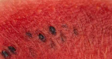A slice of ripe watermelon rotates on a plate. Close up of watermelon pulp with seeds inside.