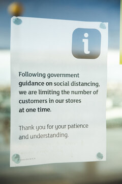 22/10/2020 Manchester, England supermarket window showing a printed out piece of paper reading following government guidance on social distancing, we are limiting the number of customers