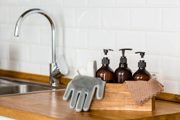 Wooden box with cleaning supplies, gloves, sponges on a modern wooden table. Stylish cleaning kit...