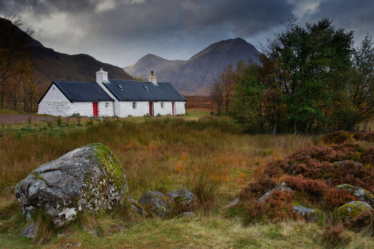 Black rock cottage, Glencoe, Scotland with mountain scenery in background.