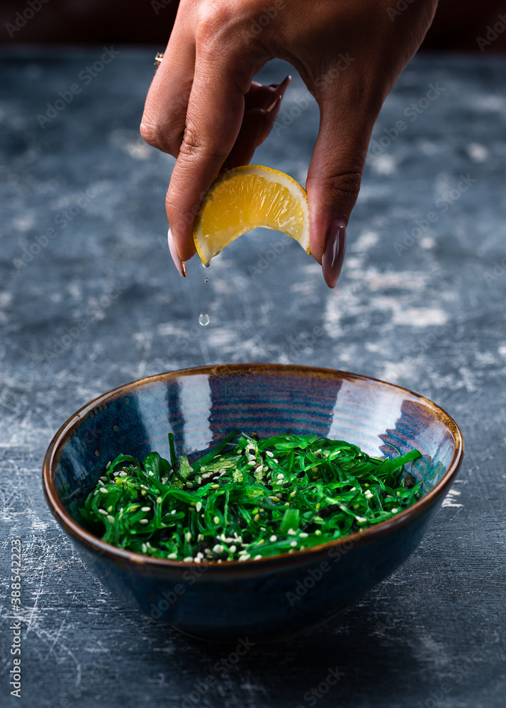 Sticker a woman's hand pours lime over chuka salad