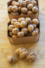 Walnuts on table in hard shells, group of dry ripened fruits in cardboard boxes, crop food ingredients ready for cooking