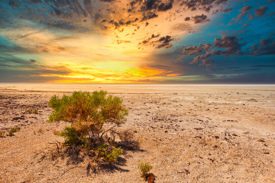 Dramatic Sunset At Salt Lake Kati Thanda Lake Eyre In The Australian Outback Of South Australia With Dark Colored Clouds And Yellow Orange Light From The Setting Sun