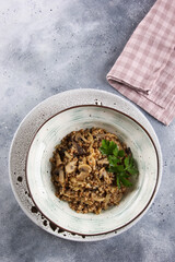 Russian cuisine. Buckwheat porridge with fried mushrooms, onions and parsley in a light plate on a gray background. Background image, copy space. Flatlay, top view