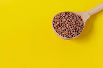 Yellow background with wooden spoon full of lentils