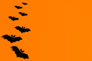 Fototapeta na wymiar orange background with a flock of black paper bats for Halloween, black paper bat silhouettes on an orange background, Halloween concept, copyspace, flatlay, top view, overhead