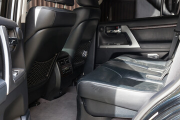 The open tailgate of the SUV overlooks the spacious, tall passenger seats covered in black leather and gray carpeted floors in a family-friendly dry-cleaned car. Pre-sale preparation.