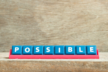Tile letter on red rack in word possible on wood background