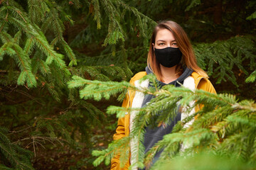 Naklejka premium Woman standing in the forest, among trees in the mask
