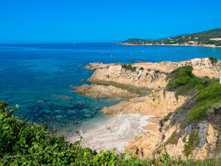 Felsige Küste und Sandstrand in der Balagne-Region von Korsika mit türkisfarbenem Mittelmeer und...