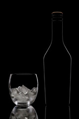 silhouette of bottle and glass with ice on a black background