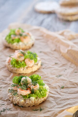 Healthy food: toast with cottage cheese, lettuce, shrimp and dill on crumpled baking paper. Shot in a high key. Vertical image.