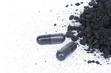 Natural black broken wood charcoal with activated charcoal capsule isolated on white background....