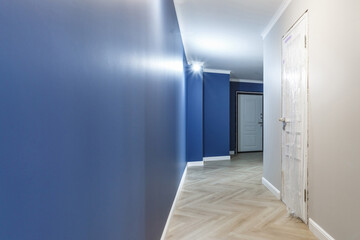 Empty unfurnished corridor with minimal preparatory repairs with crown moulding. interior of white and blue walls