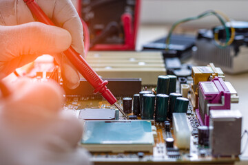 Technician man epair computer, work on motherboard by using multi meter.