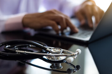Male doctor typing on a laptop computer.